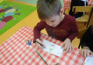 Chłopiec projektu swój banknot, rysuje kredkami.